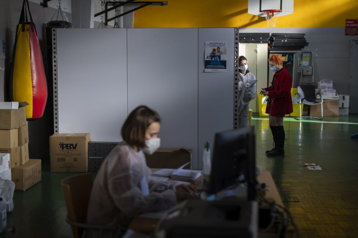 A medical worker, on the right, prepares to perform nasal tests, at a COVID-19 testing site, in Nantes, western France, Friday, Dec. 31, 2021.