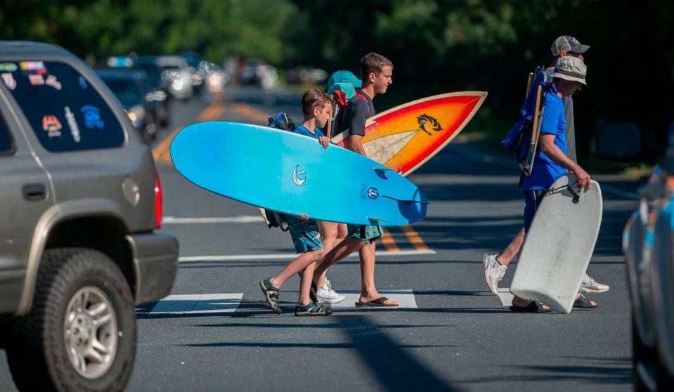 Beachgoers cross congested NC 12 on Sunday, June 27, 2021 in Southern Shores, N.C. Traffic is particularly heavy on Saturday and Sunday during the peak vacation season. At the intersection of NC 12 and Hillcrest Dr., traffic was crawling as vacationers use the only two lane road to Duck and Corolla on the northern outer banks.