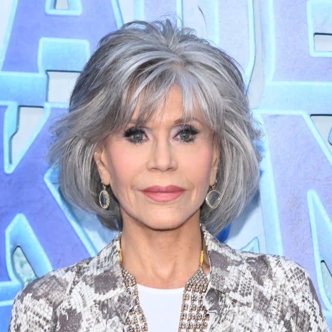 Woman with short hair in patterned jacket and layered necklaces at an event