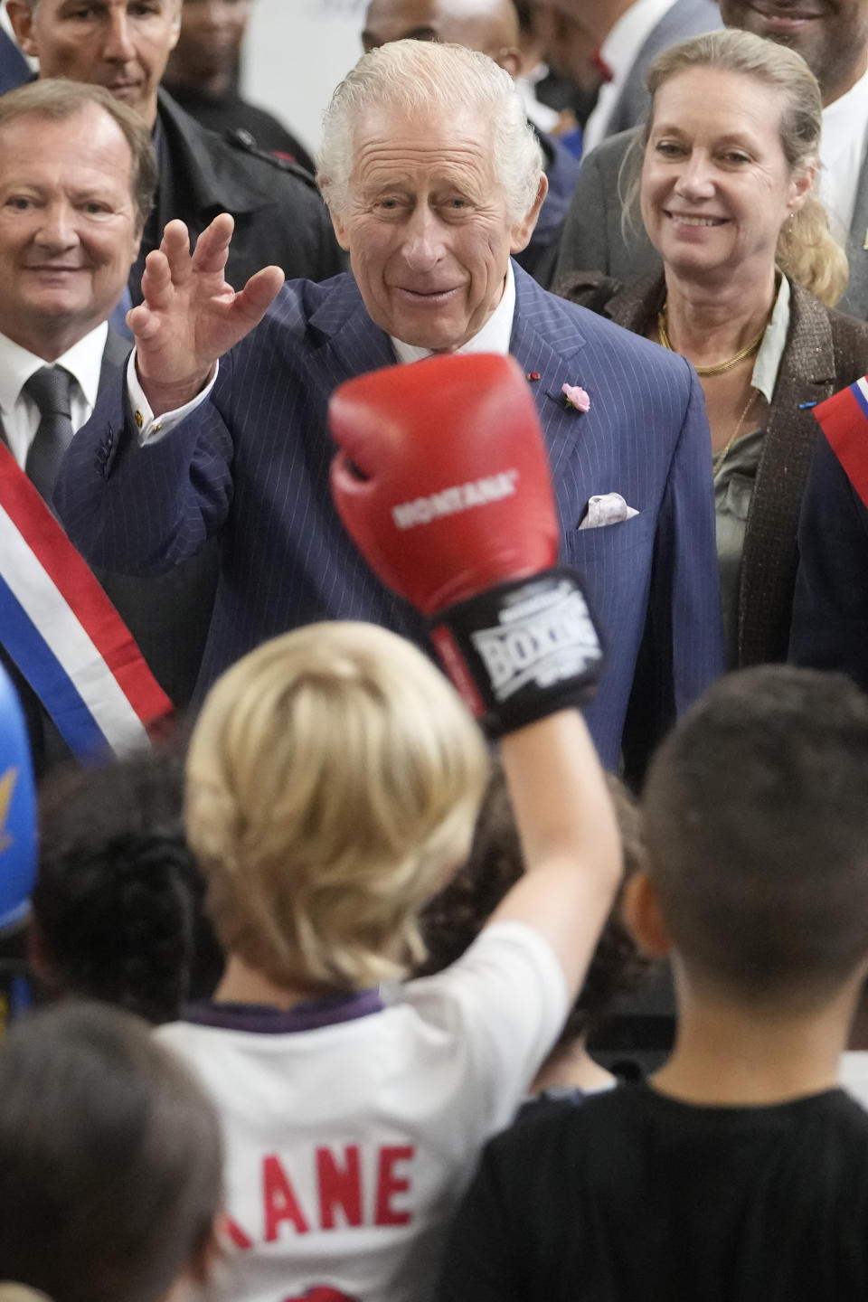 Britain' s King Charles III waves to children exercising boxing during a visit to a gymnasium, Thursday, Sept. 21, 2023 in Saint-Denis, outside Paris. (AP Photo/Thibault Camus)