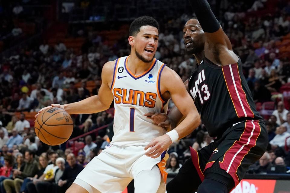 Phoenix Suns guard Devin Booker (1) dribbles as Miami Heat center Bam Adebayo (13) defends during the first half of an NBA basketball game Monday, Nov. 14, 2022, in Miami.