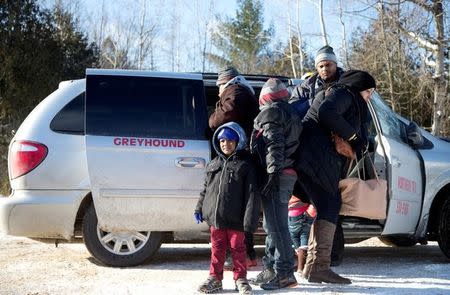 A family which claimed to be from Sudan, piles out of a Northern Taxi which drove them to the U.S.-Canada border in Champlain, New York, U.S., February 17, 2017. REUTERS/Christinne Muschi/Files