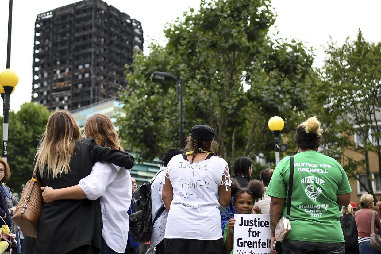 Support: Mourners hug in the shadow of the burnt-out tower block: Getty Images