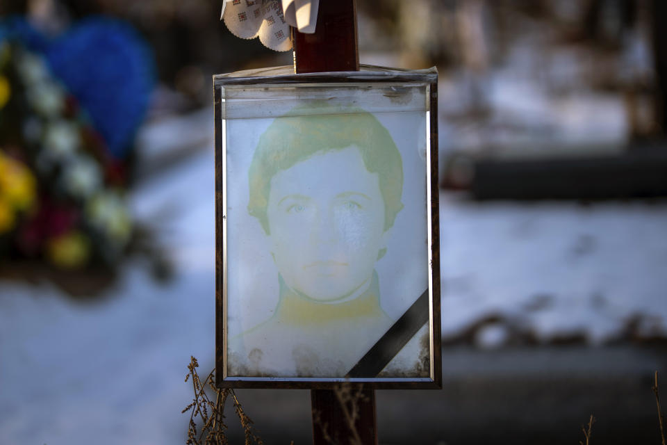 A faded portrait of Olena Serhiivna, 54, sits on her grave at a cemetery in Kyiv, Ukraine, on Thursday, Feb. 9, 2023. She was buried on April 4, 2022. (AP Photo/Emilio Morenatti)