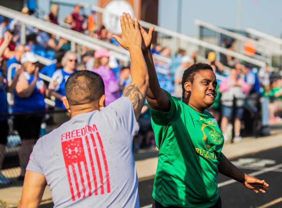 Tangie Lewis of the Binet Bulldogs receives a high five from Manuel Lema after completing her race at the Kentucky Special Olympics Area 4 track meet at Mercy Academy in Louisville, Ky on May 14, 2022.