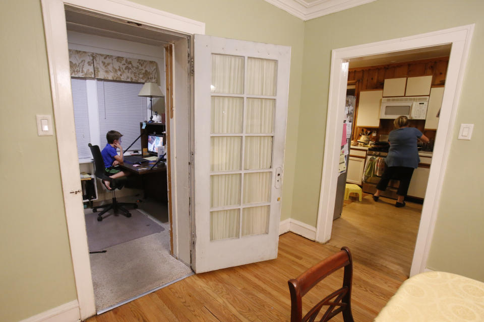 In this Saturday, Sept. 25, 2018, photo, Henry Hailey, 10, left, watches videos on YouTube while his mom, Barb Hailey, cooks dinner in Chicago. Screens have invaded the lives of young people on various levels, from social networking to school, making it difficult for parents to limit screen time. How much is too much? Some experts say the focus should instead be on how children are doing in school and functioning in the world, as well as how physically active they are. (AP Photo/Martha Irvine)