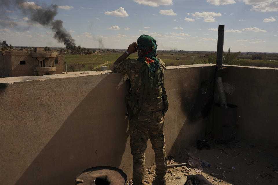 A U.S.-backed Syrian Democratic Forces (SDF) fighter watches black smoke billow from the last small piece of territory held by Islamic State militants as U.S. backed fighters pounded the area with artillery fire and occasional airstrikes in Baghouz, Syria, Sunday, March 3, 2019. (AP Photo/Andrea Rosa)