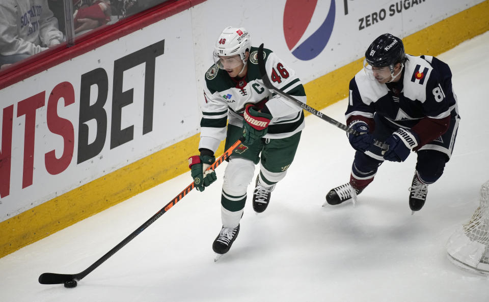 Minnesota Wild defenseman Jared Spurgeon, left, collects the puck as Colorado Avalanche center Denis Malgin defends in the first period of an NHL hockey game, Wednesday, March 29, 2023, in Denver. (AP Photo/David Zalubowski)