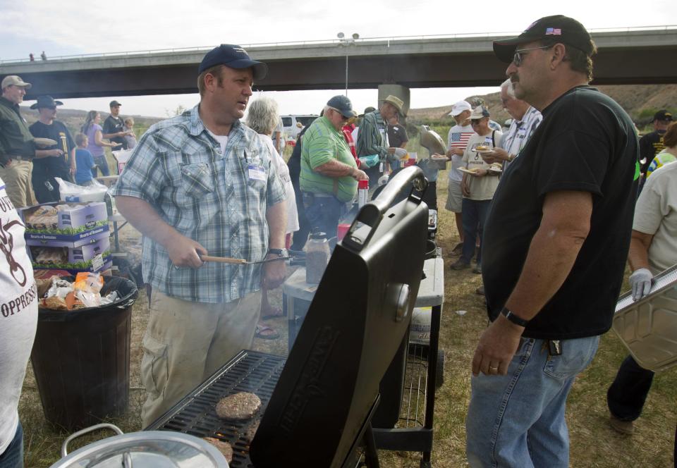 Dave Bundy (L), a son of rancher Cliven Bundy, talks with Larry Skaggs of Overton, Nevada as he cooks hamburgers during a Bundy family "Patriot Party" near Bunkerville, Nevada, April 18, 2014. (REUTERS/Steve Marcus)