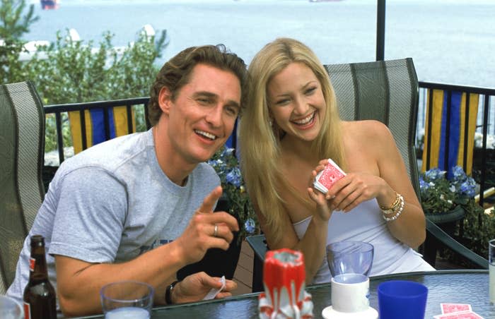 Matthew McConaughey and Kate Hudson share a laugh while playing cards at an outdoor table by the water in a scene from "How to Lose a Guy in 10 Days"