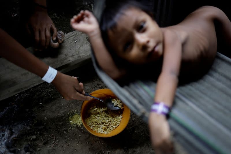 Un niño yanomami es alimentado por su madre con una mezcla de arroz y farofa mientras recibe atención sanitaria en el alojamiento utilizado para albergar a los enfermos, en la unidad sanitaria del Centro de Base de Auaris, en tierra indígena yanomami, estado de Roraima