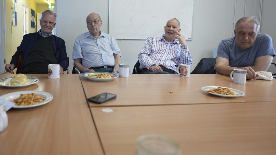 Alan Tucker, second right, listens at the weekly lunch meeting of some 20 retired men at the Tredegar community centre in Bow, in east London, Thursday, May 16, 2024. Passing around plates of cheese and crackers and slices of crème cake, they drank steaming coffee and tea. What they wanted was a chance to vent about the problems facing Britain and the fact that no one is listening to them as the country prepares for an election later this year. (AP Photo/Alastair Grant)