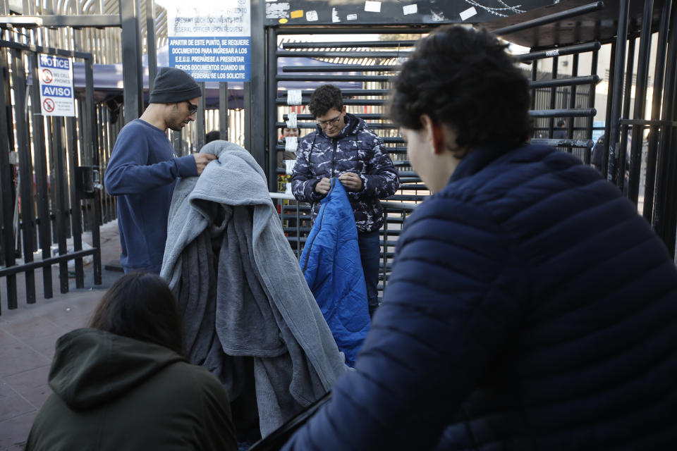 Activists for migrant rights pack their belongings after accompanying a group of Honduran asylum seekers at San Diego's Otay Mesa port of entry, seen from Tijuana, Mexico, Tuesday, Dec. 18, 2018. Six Honduran asylum seekers spent a chilly night camped out on a tiny patch of U.S. soil at a San Diego border crossing seeking to have their claims processed. (AP Photo/Moises Castillo)