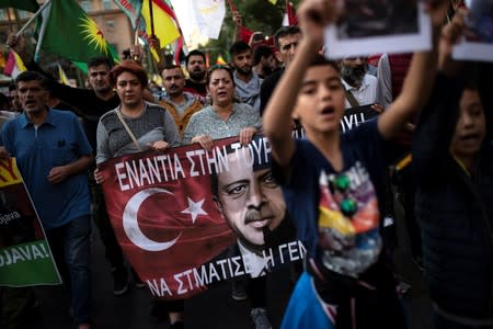 Kurds living in Greece hold a banner depicting Turkish President Tayyip Erdogan during a demonstration against Turkey's military action in northeastern Syria, in Athens