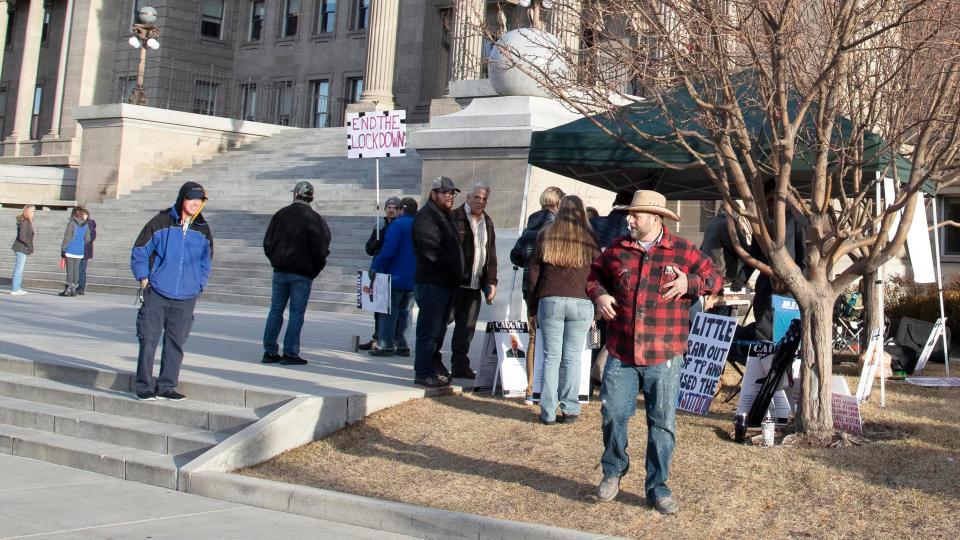 Ammon Bundy, right, arrested twice last summer at the Idaho Capitol, returns Monday, Jan. 11, 2021, to deliver protest signs to demonstrators on the first day of the Idaho Legislature in Boise.