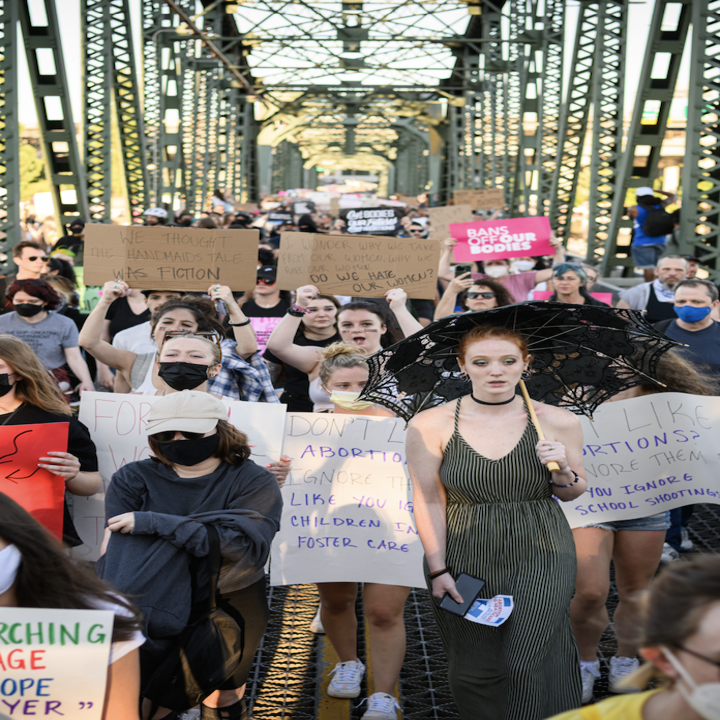 people crowded on a bridge with signs