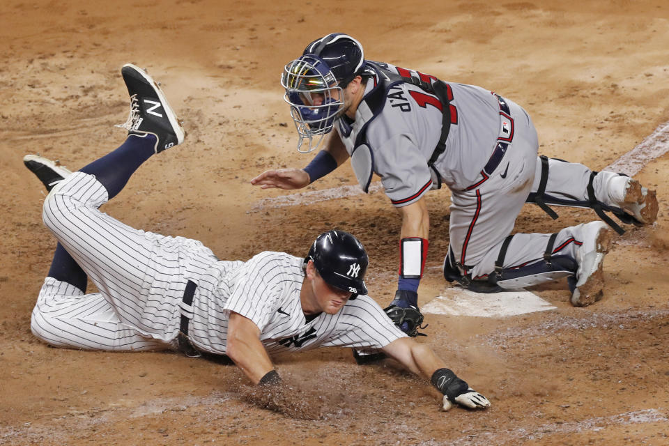 New York Yankees DJ LeMahieu, left, scores on Aaron Hick's fourth-inning double as Atlanta Braves catcher Travis d'Arnaud (16) is late with the tag in a baseball game, Wednesday, Aug. 12, 2020, in New York. (AP Photo/Kathy Willens)