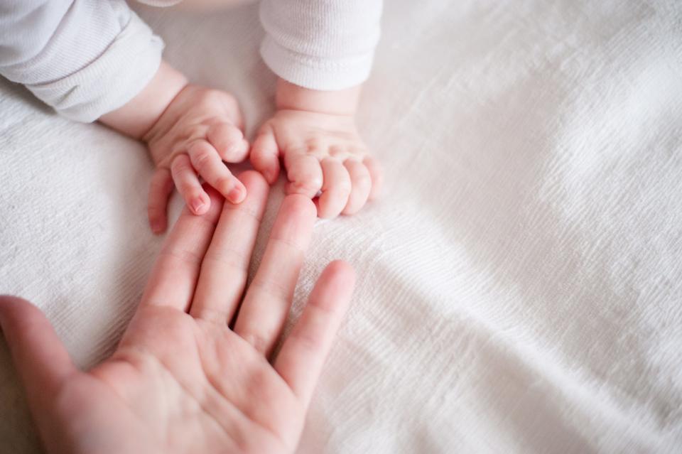 Hands of a newborn baby on mother's fingers.