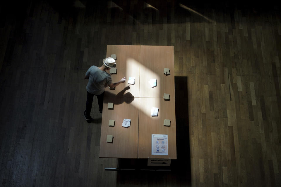 A voter picks up ballots before voting in the second round of the French parliamentary election in Lyon, central France, Sunday, June 19, 2022. French voters are going to the polls in the final round of key parliamentary elections that will demonstrate how much legroom President Emmanuel Macron's party will be given to implement his ambitious domestic agenda. (AP Photo/Laurent Cipriani)