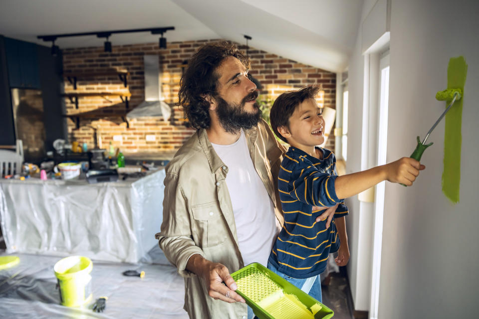 Close up of a father and son painting the walls of their home