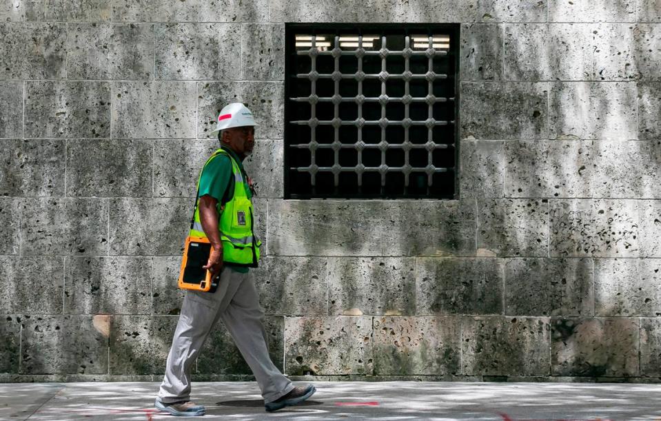 Un trabajador de la construcción camina por la calle Flagler junto a una ventana enrejada en la base del Miami-Dade Cultural Center, que parece una fortaleza, en el downtown de la ciudad.