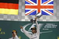 Formula One - F1 - Brazilian Grand Prix - Circuit of Interlagos, Sao Paulo, Brazil - 13/11/2016 - Mercedes' Lewis Hamilton of Britain raises his trophy during the victory ceremony after winning the race as second placed finisher and teammate Nico Rosberg of Germany (L) looks on. REUTERS/Nacho Doce