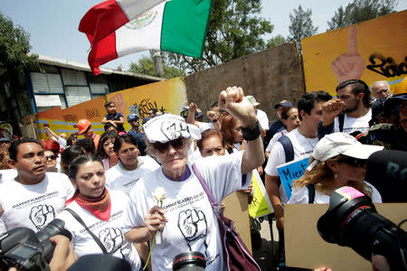 Families of the Tlalpan housing project, affected by the September 2017 earthquake, raise their fist during a minute of silence to honour the victims of the quake in Mexico City, Mexico September 19, 2018. REUTERS/Daniel Becerril