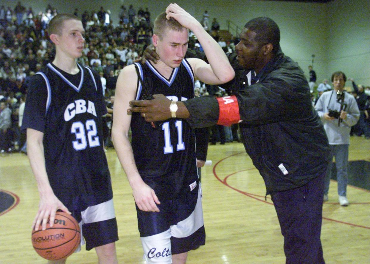 CBA's Jason Krayl is comforted by Elizabeth Public School security guard John Adams (right) and teammate Mike Skrocki (left) after losing the Parochial A State Championship against Seton Hall Prep at the Dunn Center in 2000.