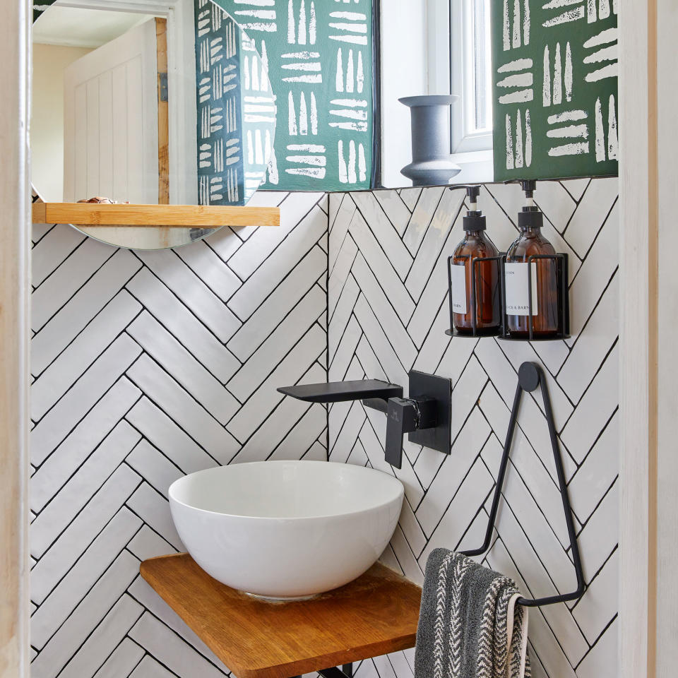 Cloakroom with round white basin on a chopping board shelf and herringbone metro tiles