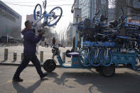 A worker collects bicycles from a bike-sharing service in Beijing Thursday, Feb. 25, 2021. The state of the world's second largest economy takes precedence among the myriad issues presented by Chinese Premier Li Keqiang in his address at the National People's Congress opening session to take place on Friday, March 5. 2021. (AP Photo/Ng Han Guan)