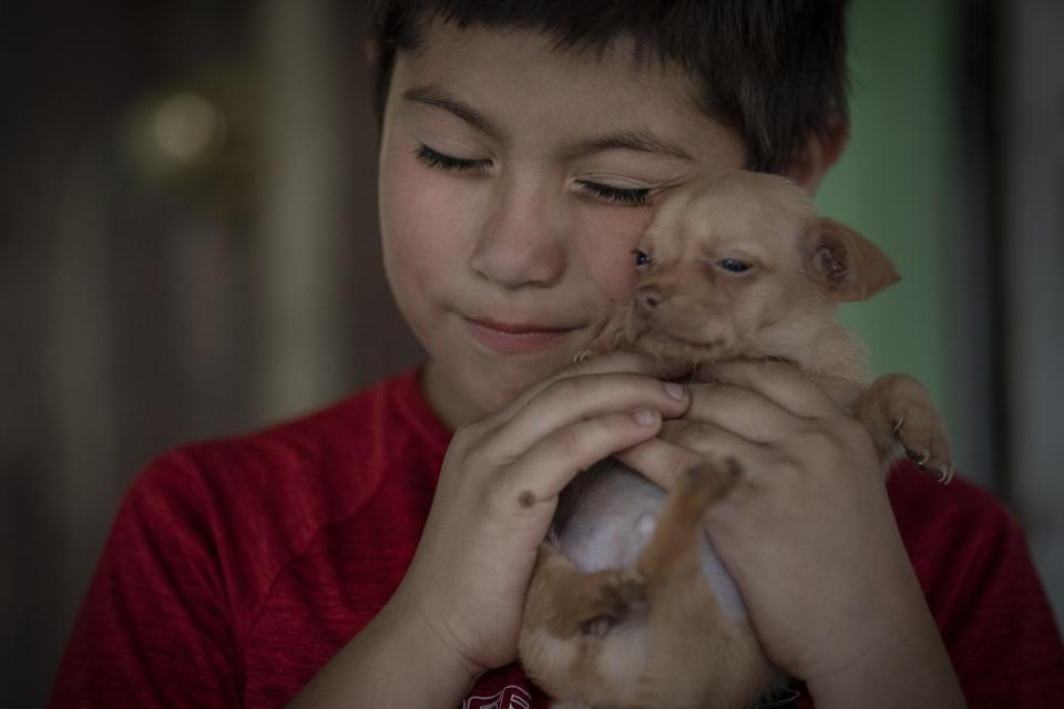 Eight-year-old Jeremiah Lennon hugs his puppy named "Peanut" at his home on Saturday, May 28, 2022, in Uvalde, Texas. The third grader had been in classroom 112, just next to the rooms where the shooter holed up. The 15 kids in his class sat on the ground in the corner, as quiet as they could be, he said. The gunman tried to get in but the door was locked. Jeremiah said he was mad at first, because they were missing recess. He was also terrified: "I was scared I would get shot, my friends would get shot." (AP Photo/Wong Maye-E)