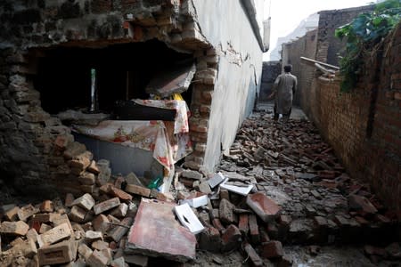A man walks over rubbles of a damaged house after an earthquake in Jatlan, Mirpur