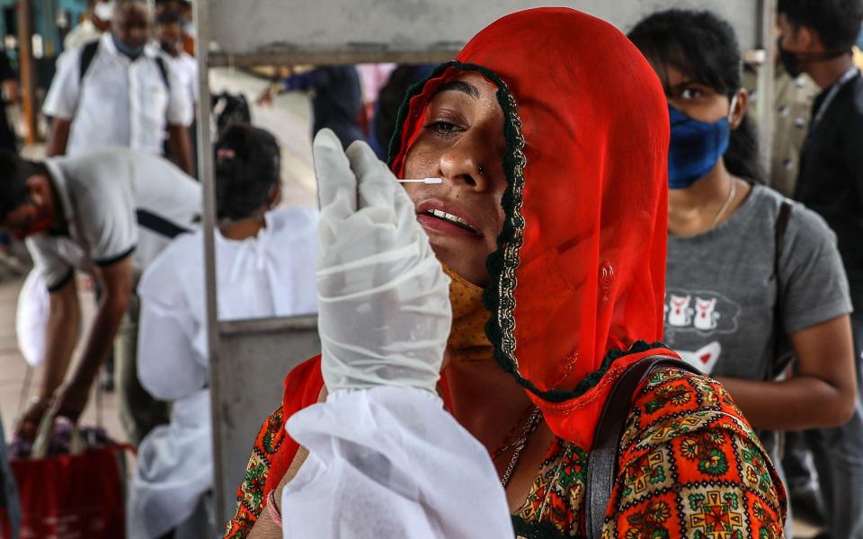 A woman undergoes a swab collection to detect Covid-19 after arriving at Dadar railway station in Mumbai, India - DIVYAKANT SOLANKI/EPA-EFE/Shutterstock