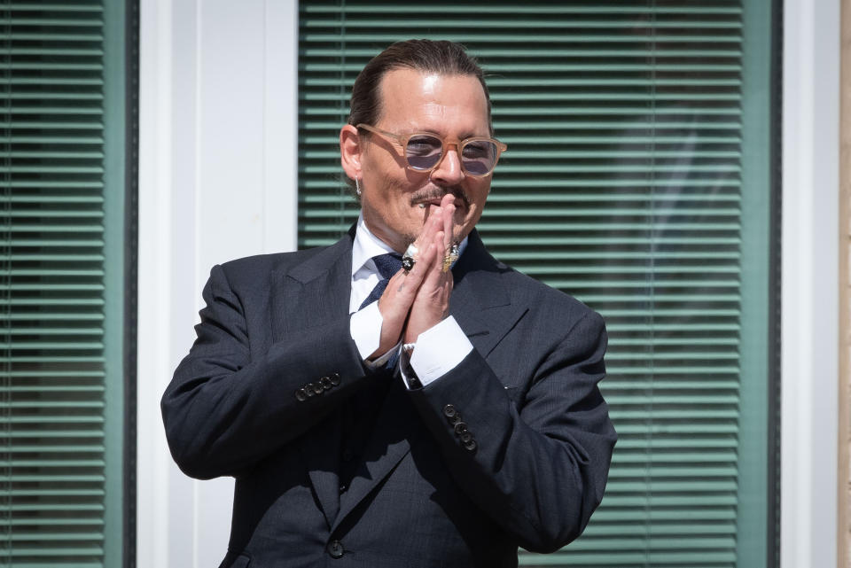 Johnny Depp holding his hands up in acknowledgment outside the courtroom