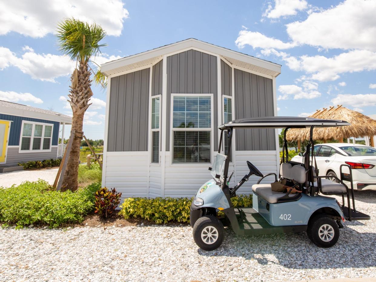 A cabana with a golf cart. Both next to a car.