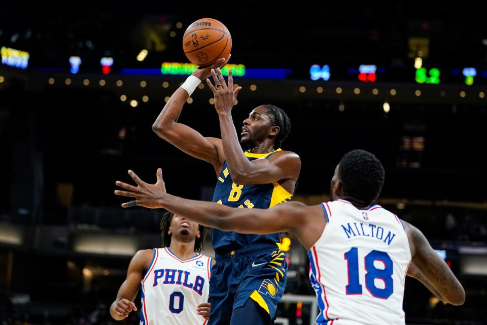 Indiana Pacers forward Justin Holiday (8) shoots over Philadelphia 76ers guard Shake Milton (18) during the second half of an NBA basketball game in Indianapolis, Saturday, Nov. 13, 2021. The Pacers defeated the 76ers 118-113. (AP Photo/Michael Conroy)