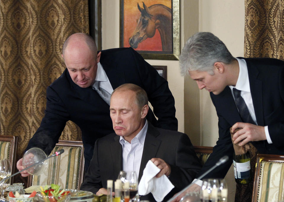 FILE - Businessman Yevgeny Prigozhin, left, serves food to Russian Prime Minister Vladimir Putin, center, during dinner at Prigozhin's restaurant, outside Moscow, Russia, Friday, Nov. 11, 2011. The final two months of Yevgeny Prigozhin's life are shrouded in mystery. When the Russian mercenary leader staged a mutiny against the country's military in June, President Vladimir Putin decried it as “treason” and vowed punishment. But then he cut a a deal not to prosecute the chief of the Wagner group. Two months later, Prigozhin’s business jet plummeted from the sky. (AP Photo/Misha Japaridze, Pool, File)