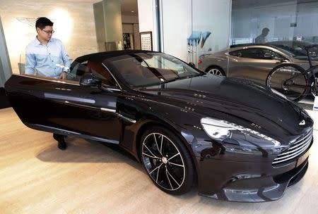 Sales Manager Raymond Liu gets into an Aston Martin Vanquish at their showroom in Singapore August 1, 2014. Supercar dealers in wealthy Singapore are fretting over their future as higher taxes, new auto loan restrictions and a shift in tastes towards less ostentatious vehicles send sales plummeting. Picture taken August 1. REUTERS/Edgar Su