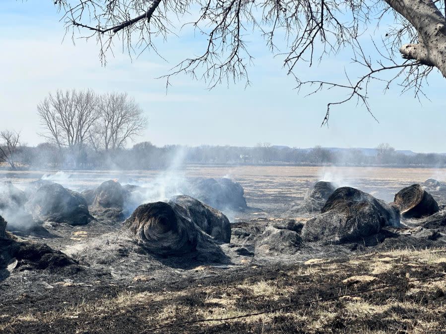 Smoke rises from smoldering hay bales outside the town of Canadian, Texas on Wednesday, Feb 28, 2024. A fast-moving wildfire burning through the Texas Panhandle grew into the second-largest blaze in state history Wednesday, forcing evacuations and triggering power outages as firefighters struggled to contain the widening flames. (AP Photo/Sean Murphy)