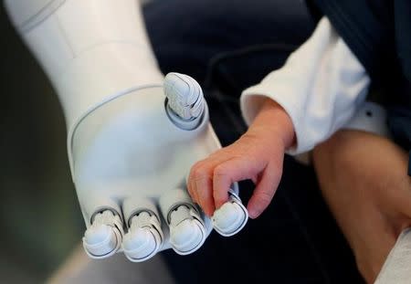 New recruit "Pepper" the robot, a humanoid robot designed to welcome and take care of visitors and patients, holds the hand of a new born baby at AZ Damiaan hospital in Ostend, Belgium June 16, 2016. REUTERS/Francois Lenoir