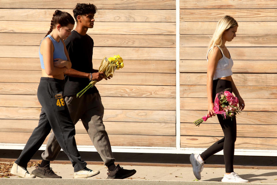 People walk to leave flowers at the scene where four women were killed in a multi-vehicle crash in Malibu, Calif., (Genaro Molina / Los Angeles Times via Getty Images)