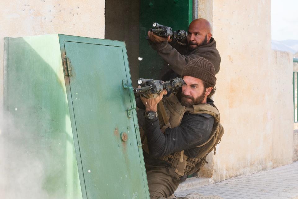 Sgt. John Kinley (Jake Gyllenhaal, front) and his translator Ahmed (Dar Salim) have each other's backs in an Afghanistan firefight in Guy Ritchie's military thriller "The Covenant."