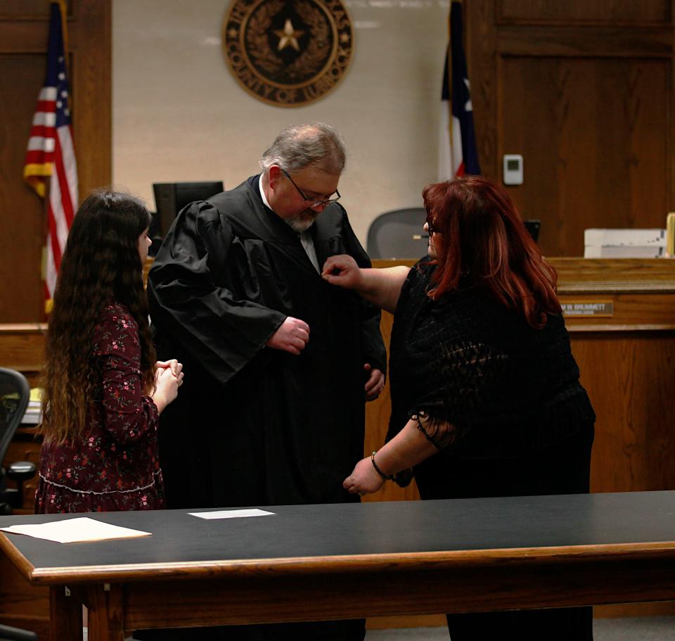 Christiana Brummett, right, helps her husband Tom don his robe after he was sworn in Tuesday as judge of Lubbock County Court at Law #2.