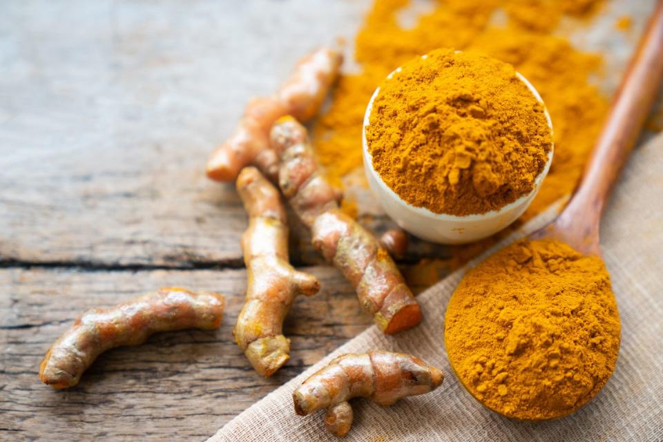 turmeric powder and fresh turmeric on wooden background