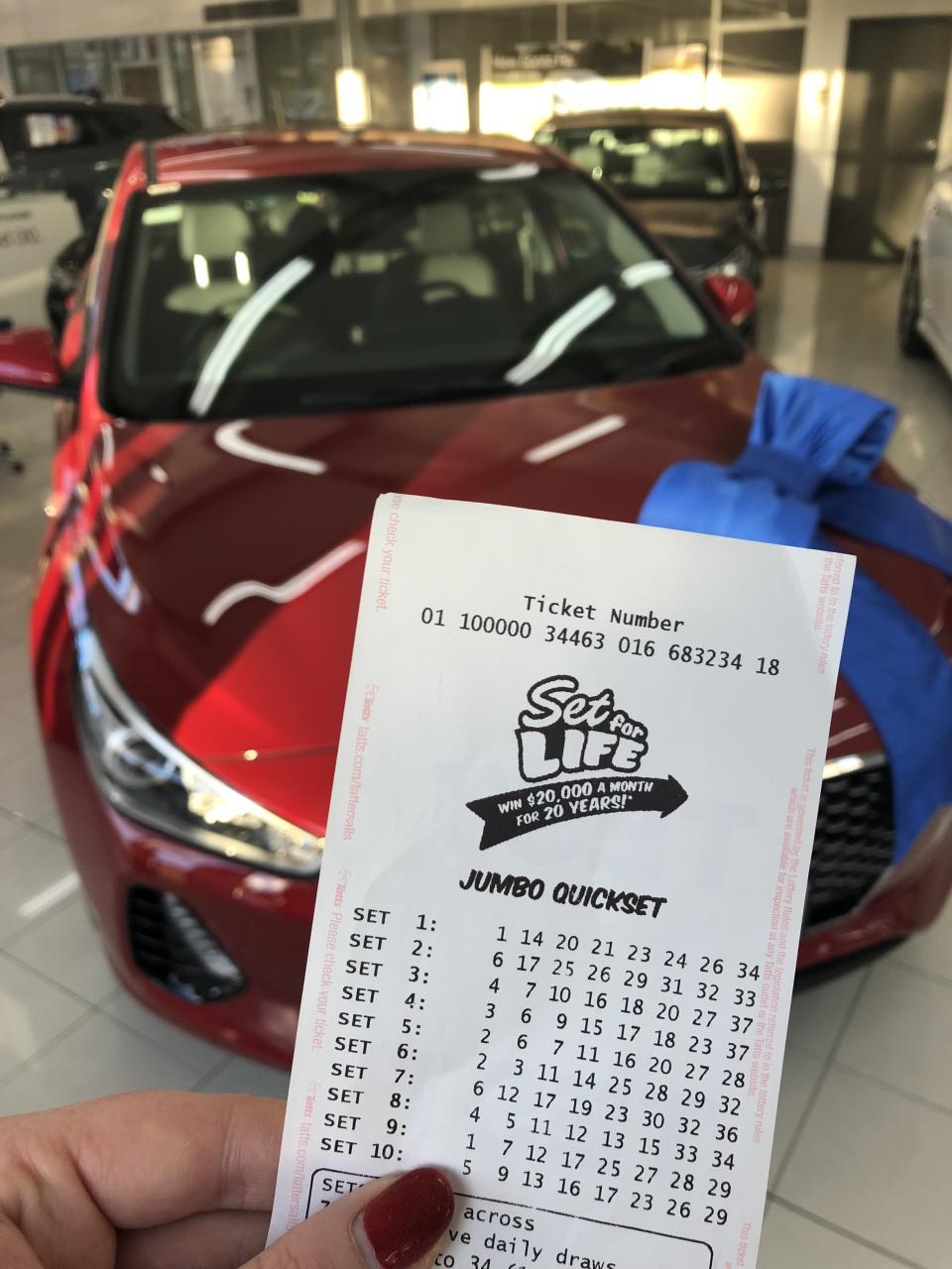 Lottery ticket in front of new car