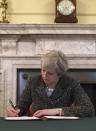 Britain's Prime Minister Theresa May signs the official letter to European Council President Donald Tusk, in 10 Downing Street, London, Tuesday March 28, 2017, invoking Article 50 of the bloc's key treaty, the formal start of exit negotiations. Britons voted in June to leave the bloc after four decades of membership. (Christopher Furlong/Pool via AP)