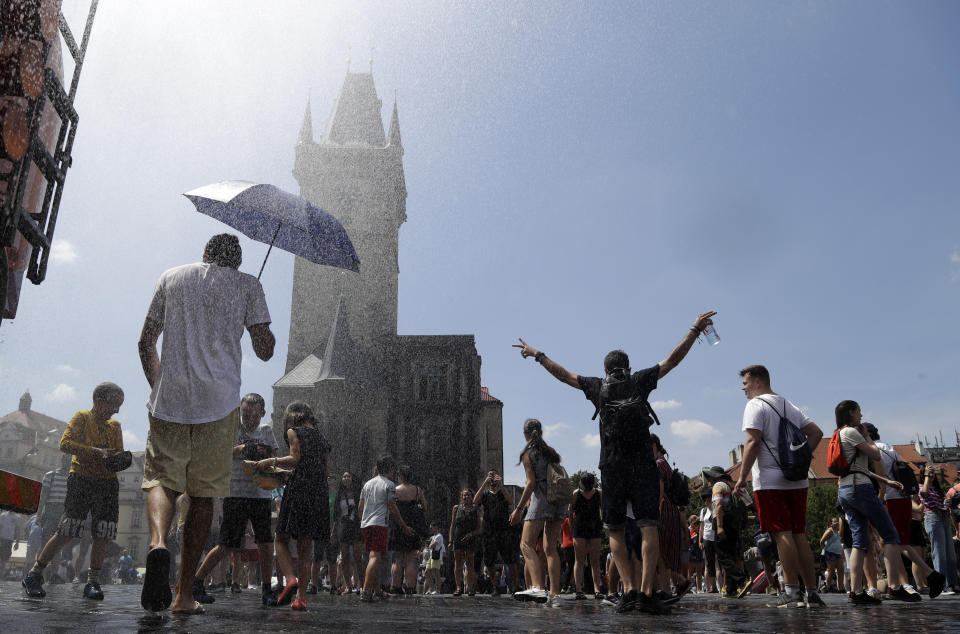 People cool down under the spray of water during a hot and sunny day at the Old Town Square in Prague, Czech Republic, Tuesday, June 25, 2019. (AP Photo/Petr David Josek)