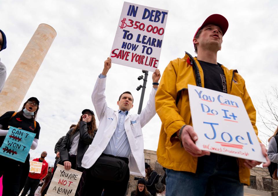 A person wearing a medical jacket holds a sign during a Cancel Student Debt rally outside the US Department of Education in Washington, DC, on April 4, 2022.