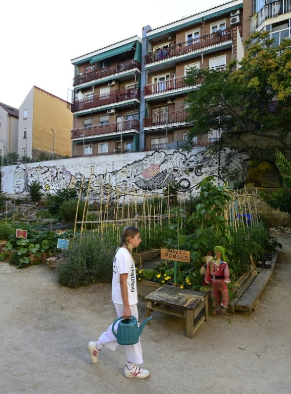 A girl carries a watering can in the urban and community garden "Esta es una Plaza" (This one is a Plaza) in Madrid, on June 17, 2015