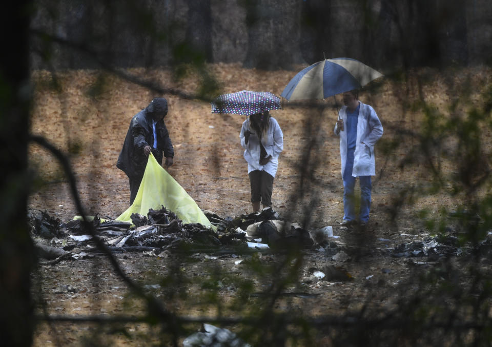 Investigators work the scene of a small plane crash in a city park, Thursday, Dec. 20, 2018, in Atlanta. A few people aboard the business jet were killed when the aircraft plunged into a football field at the park, igniting its fuel and sending thick smoke over a nearby neighborhood Thursday. (AP Photo/John Amis)